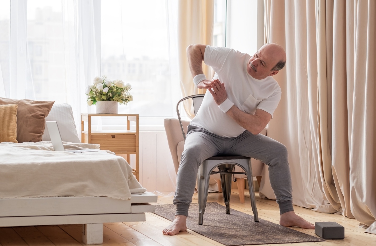 Senior man performing chair yoga.