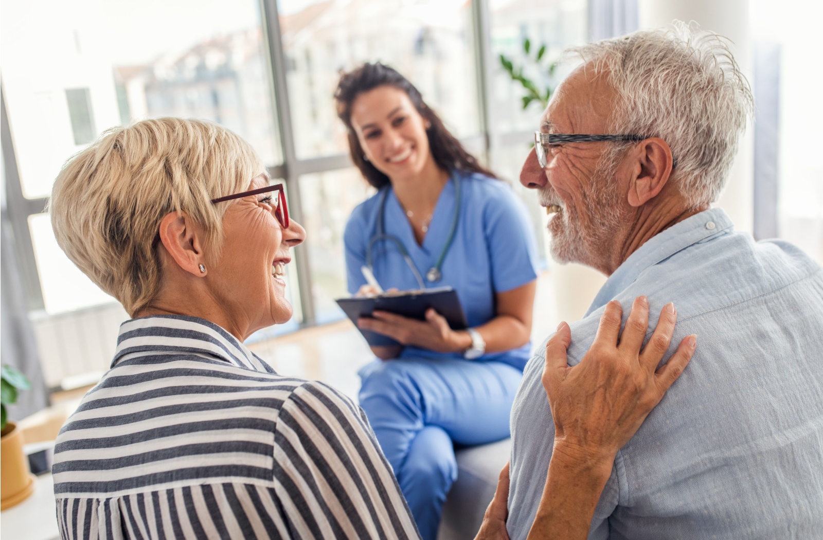 Female nurse talking with senior couple.
