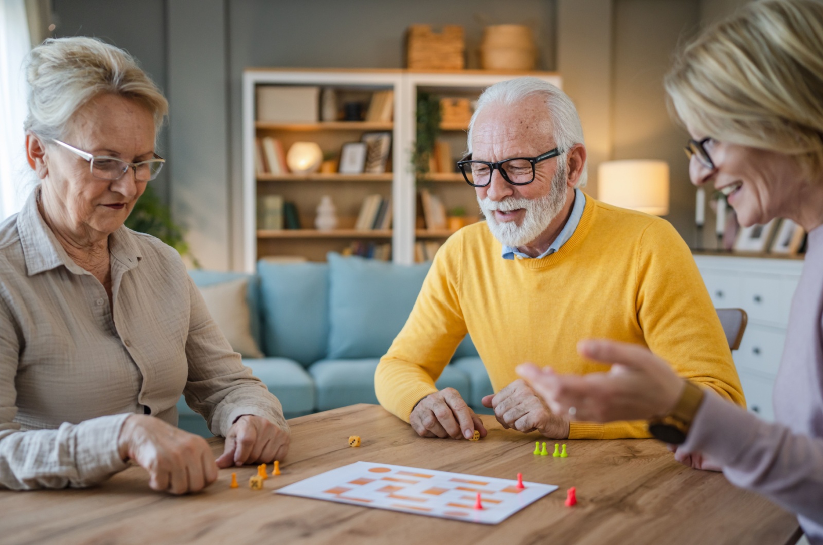 A group of seniors sitting at a table socializing and playing a board game.
