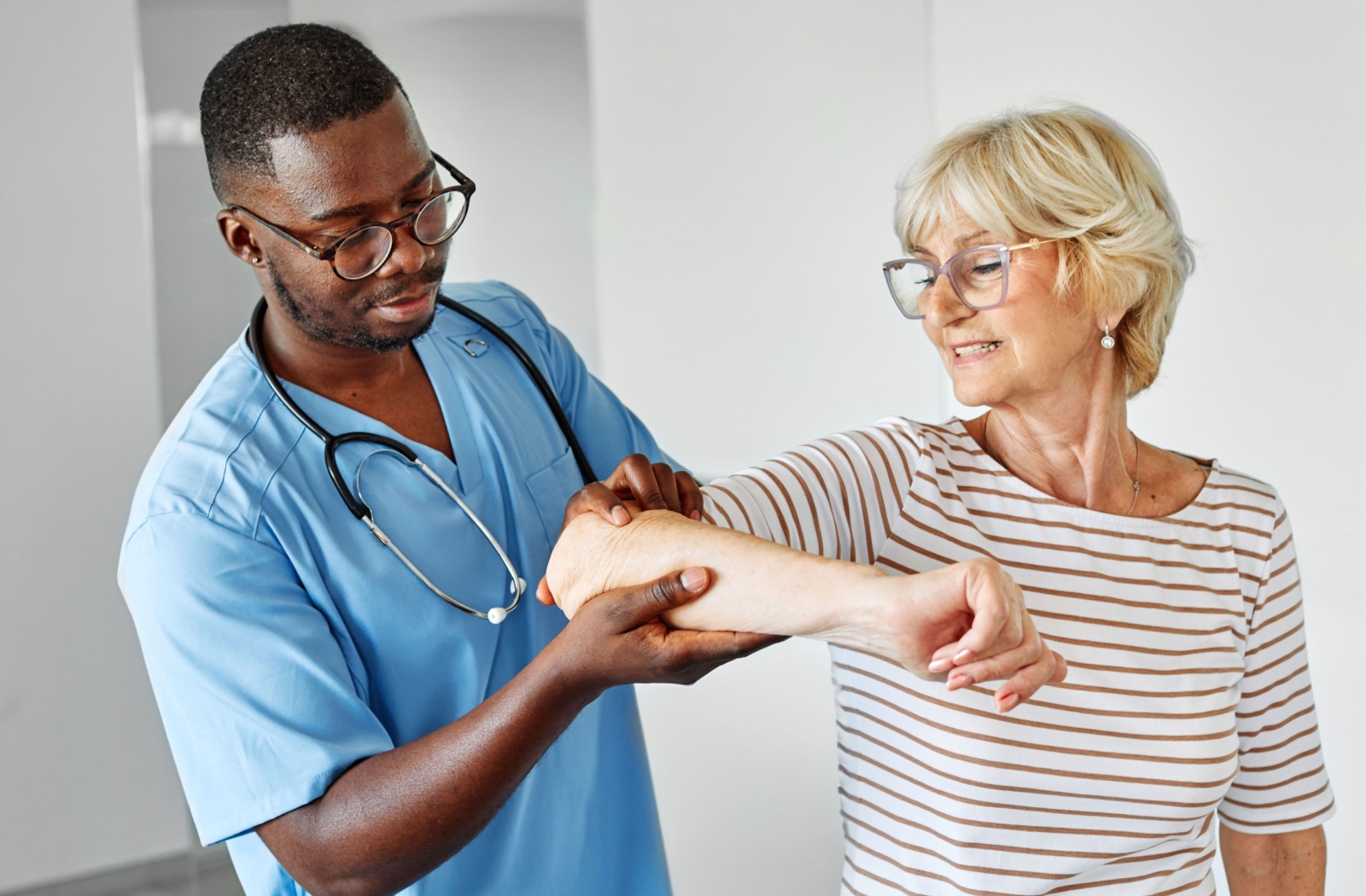 An RN lifts a senior woman's arm during a physical therapy appointment.