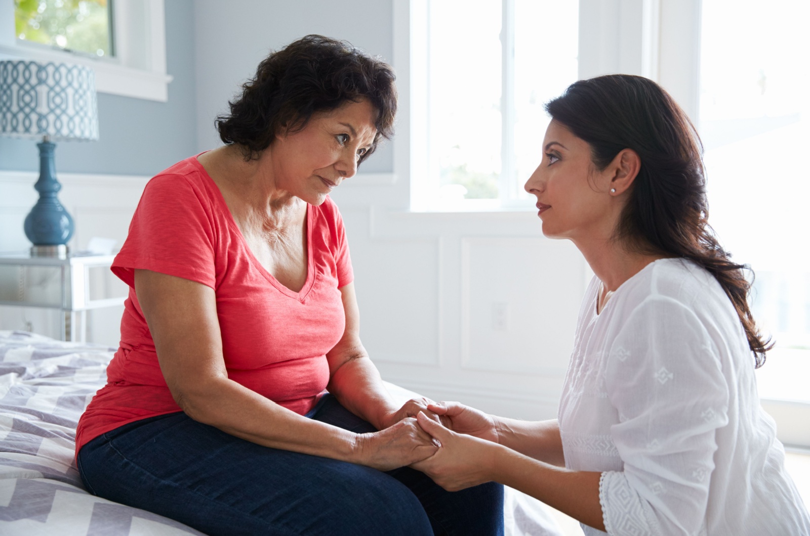 An adult child being patient while sitting in front of their parent and holding their hands