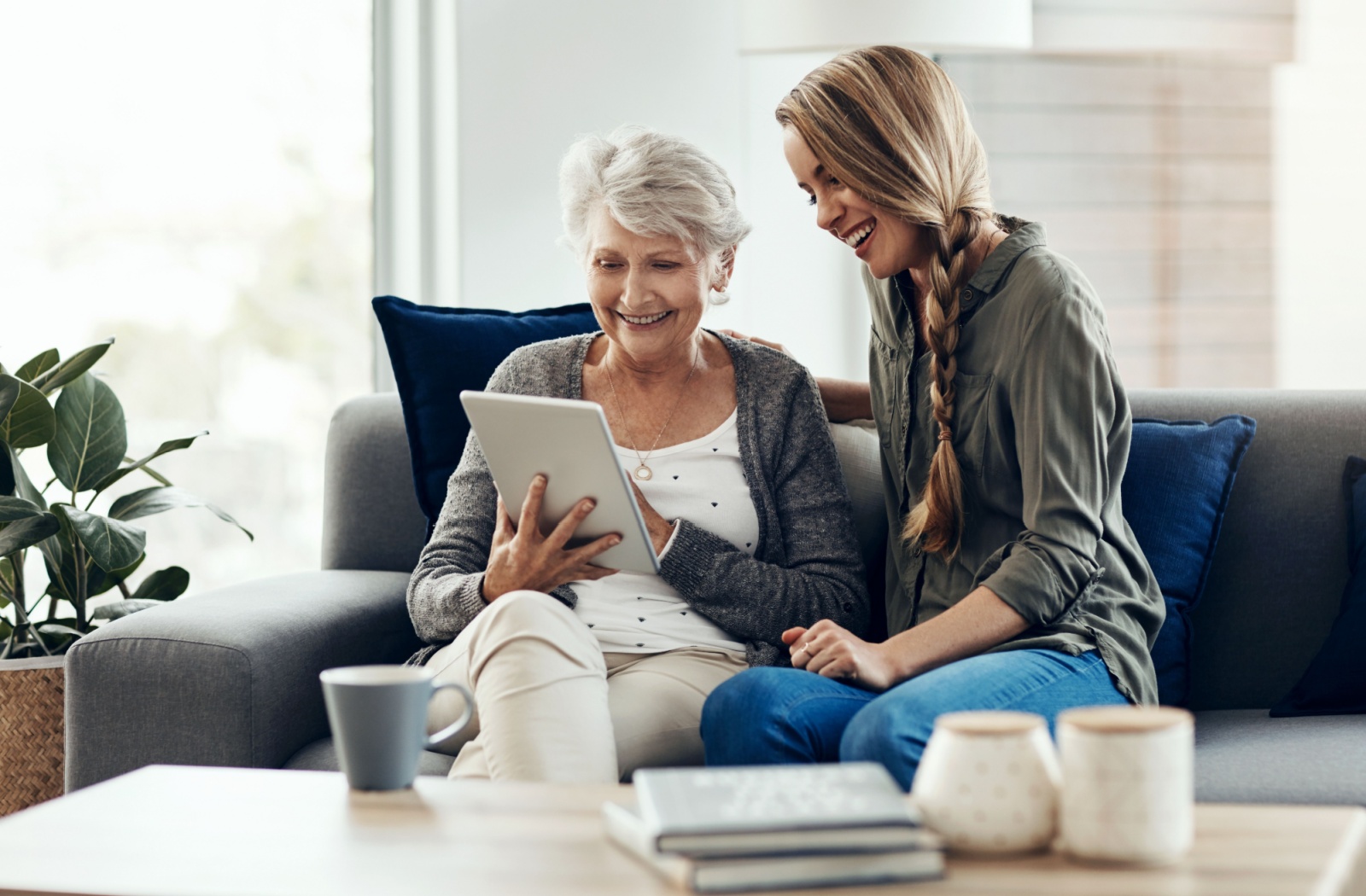 A senior mother and adult daughter exploring iPad apps and games together.