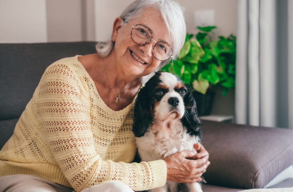 A senior resident hugs their beloved pet dog while sitting on a couch